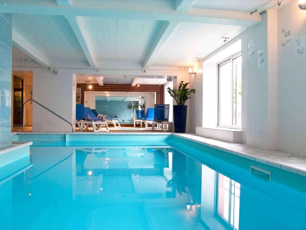 uma piscina com água azul num quarto em Mercure Epinal Centre em Épinal