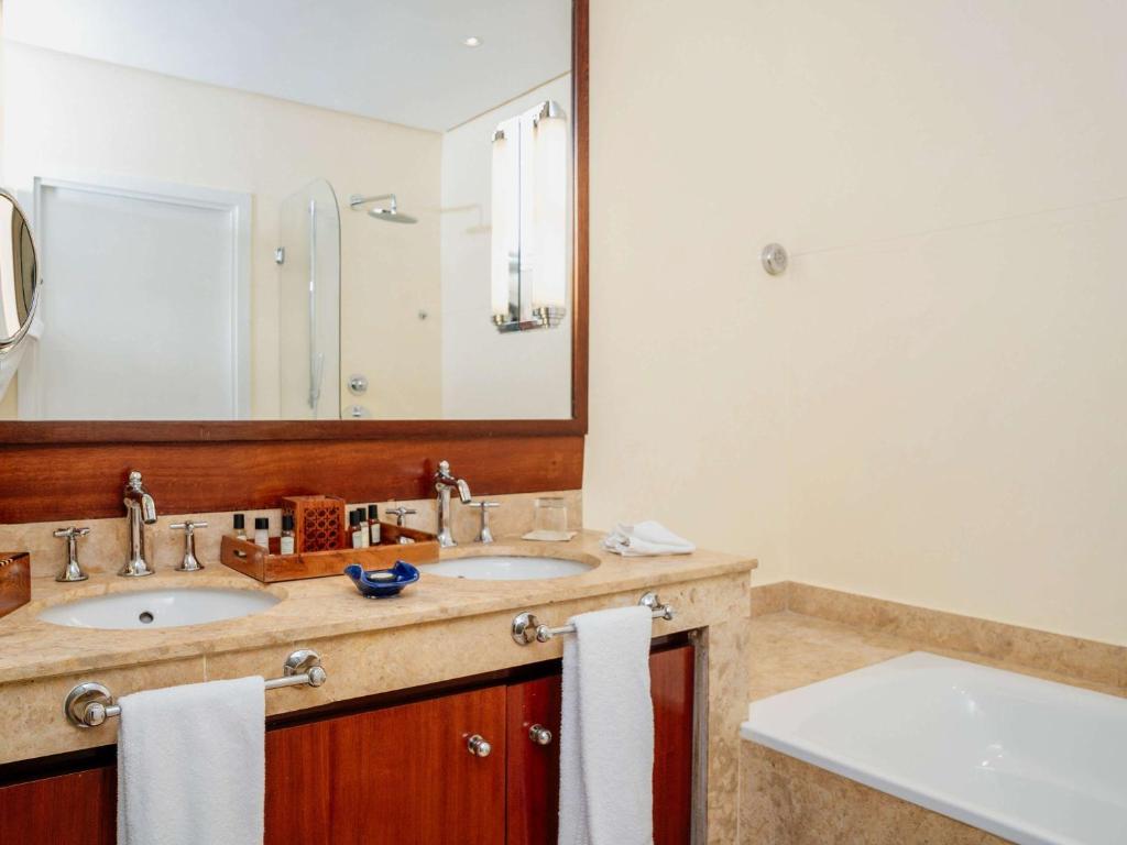 a bathroom with two sinks and a large mirror at Le Médina Essaouira Thalassa Sea & Spa - MGallery Collection in Essaouira