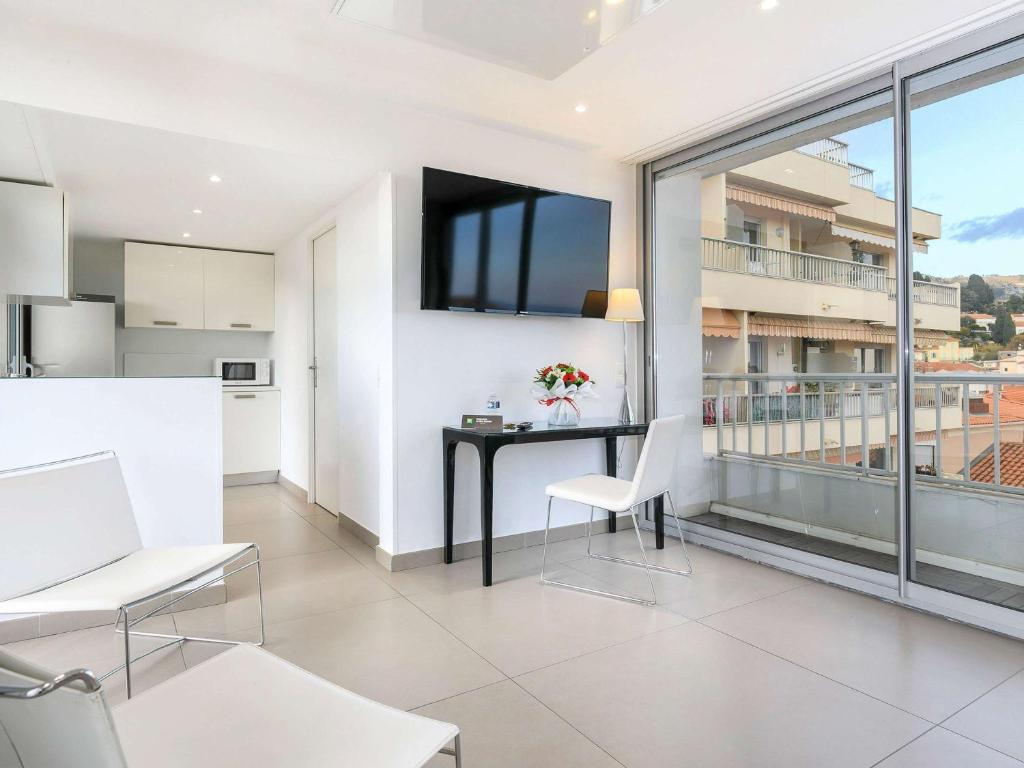 a kitchen and living room with a table and chairs at Ibis Styles Menton Centre in Menton