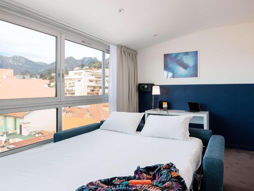a bedroom with a large bed and a large window at Ibis Styles Menton Centre in Menton