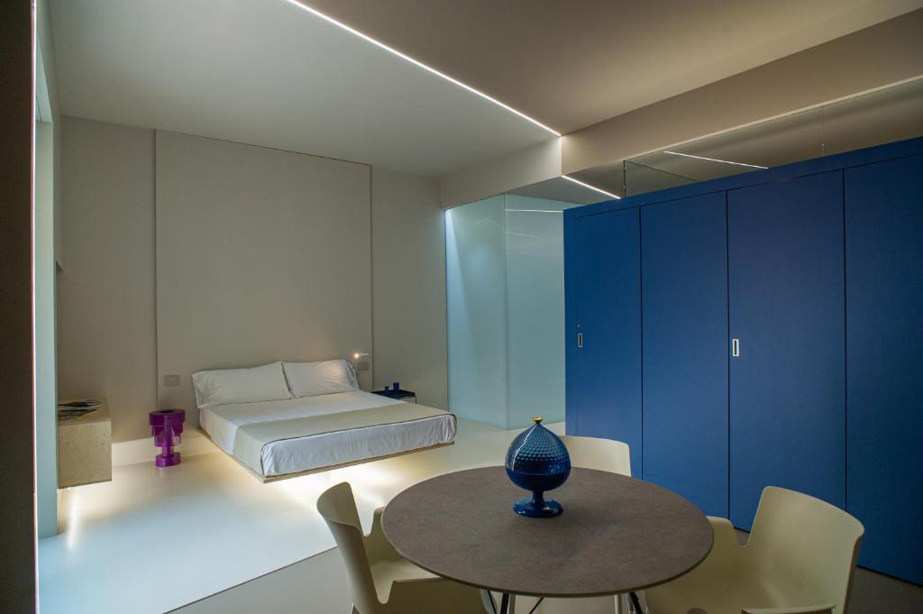 Fiveplace Design Suites & Apartments في تراباني: غرفة نوم بسرير وطاولة وكراسي