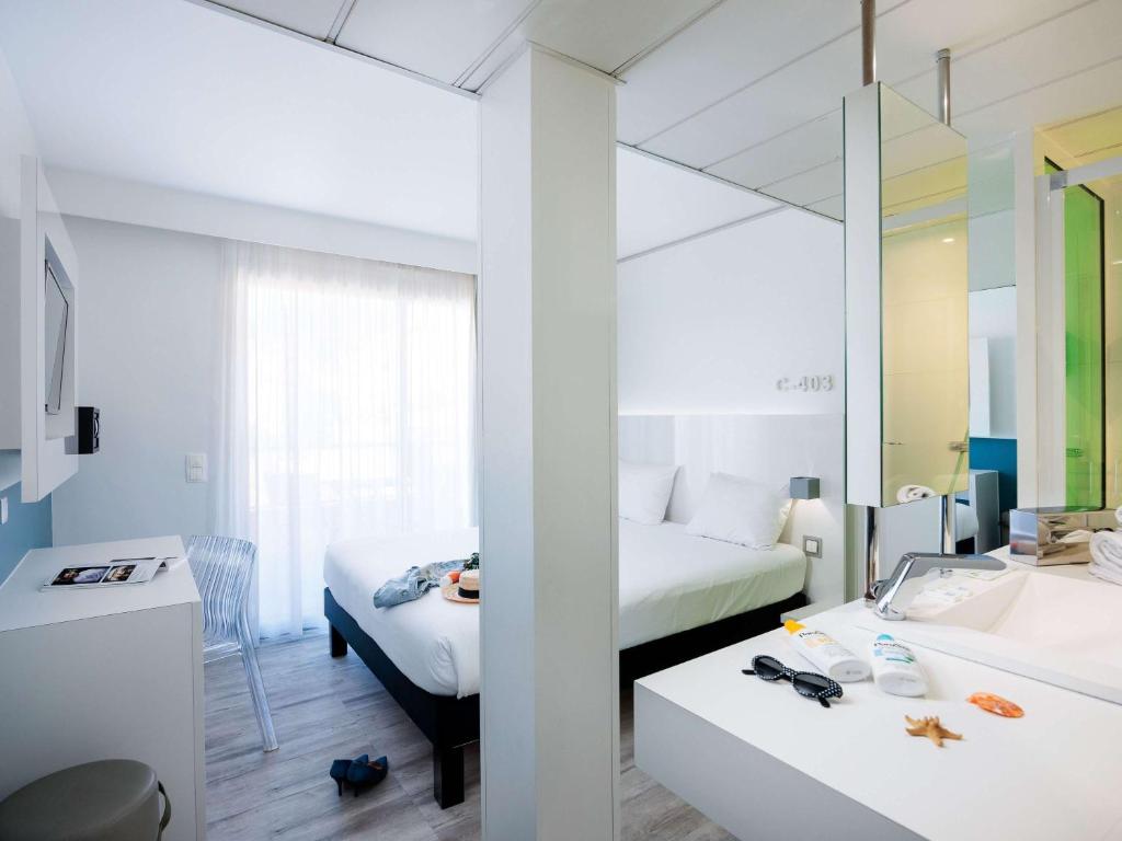 a hotel room with two beds and a mirror at Ibis Styles Menton Centre in Menton