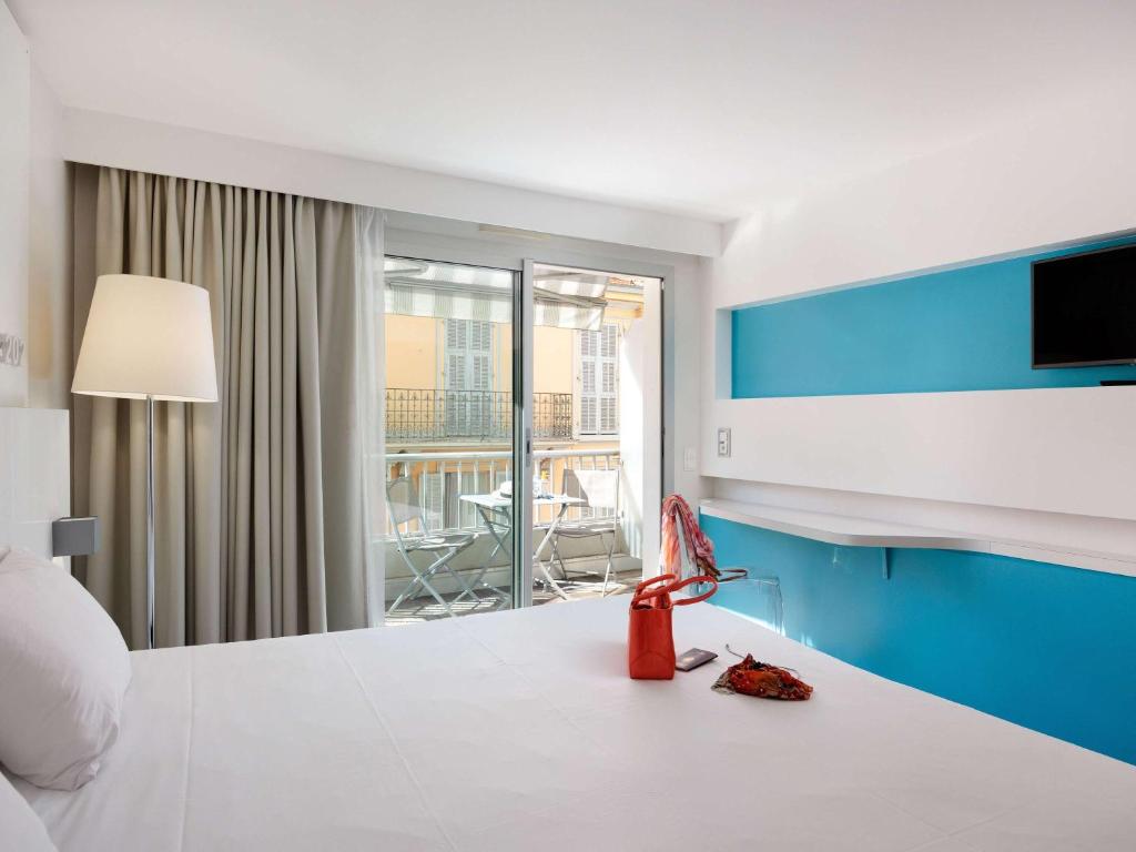 a hotel room with a bed and a view of a balcony at Ibis Styles Menton Centre in Menton