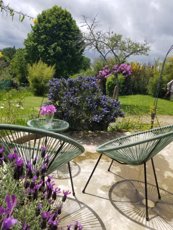 a table and chairs in a garden with purple flowers at La bohème in Saint-Julien-le-Petit