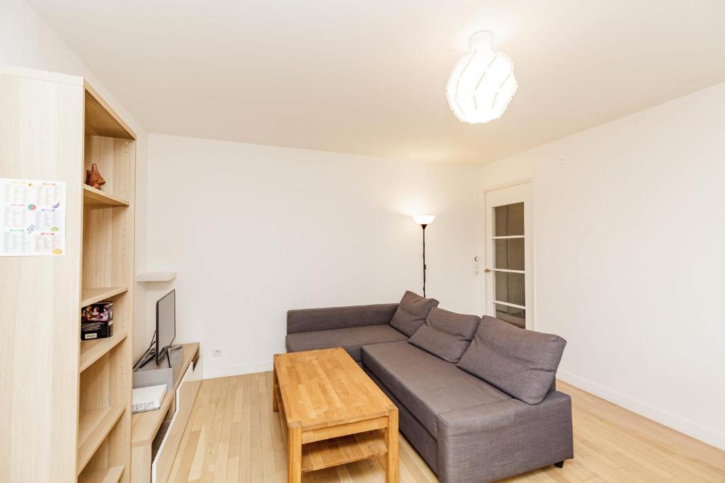 ein Wohnzimmer mit einem Sofa und einem Tisch in der Unterkunft Large apartment near Bois de Vincennes in Charenton-le-Pont