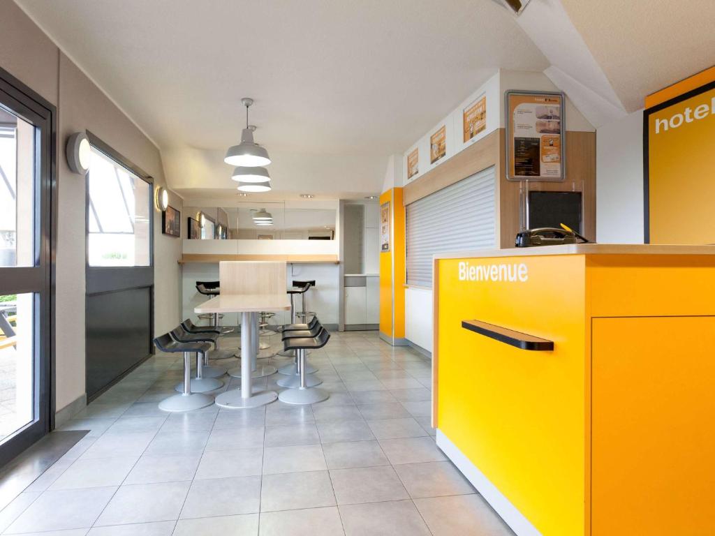 una oficina con mostrador amarillo, mesa y sillas en Unisotel Sens Nord EX F1, en Sens