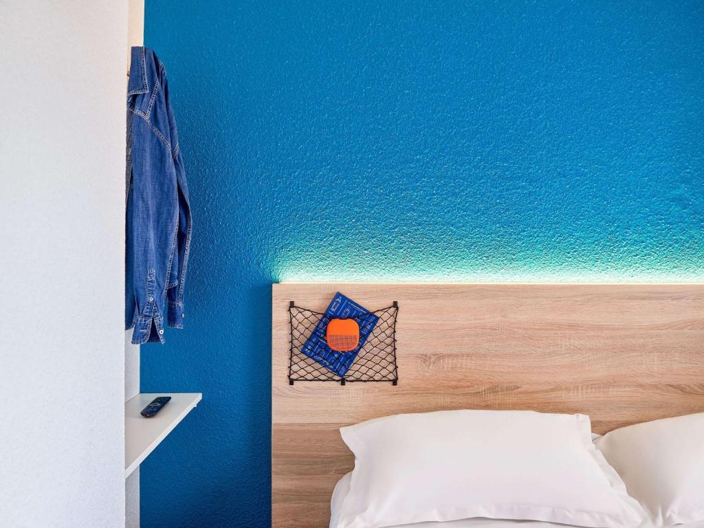 a bedroom with a blue wall and a bed with a headboard at hotelF1 Toulon Est La Valette in La Valette-du-Var
