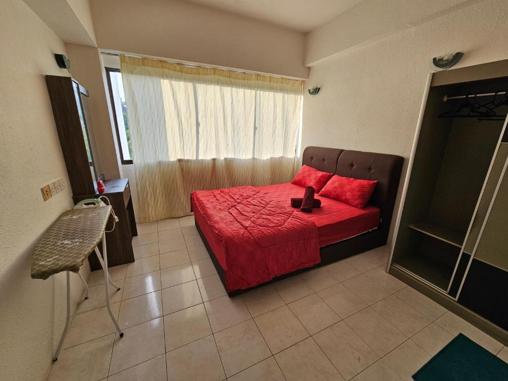 a bedroom with a red bed and a window at Bintara Guesthouse Sri Sayang Batu Ferringhi in Batu Ferringhi