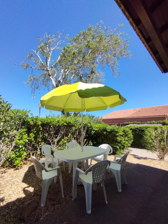 une table et des chaises avec un parapluie jaune dans l'établissement Villa Beau Soleil, à Narbonne-Plage