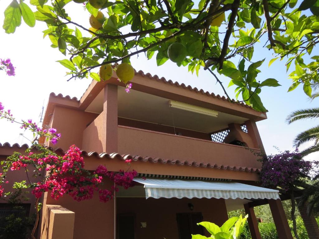 una casa con fiori rosa di fronte di Villetta Sunrise 6A a Costa Rei