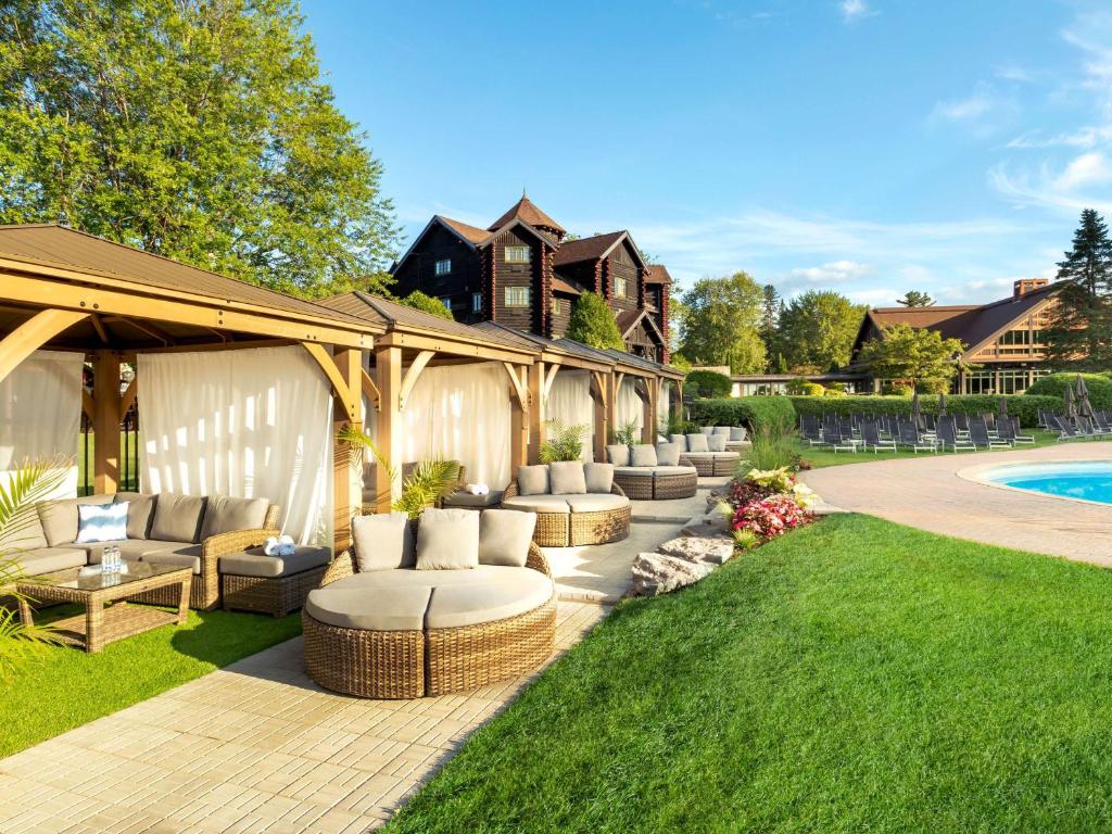 a patio with couches and a pool in a yard at Fairmont Le Chateau Montebello in Montebello