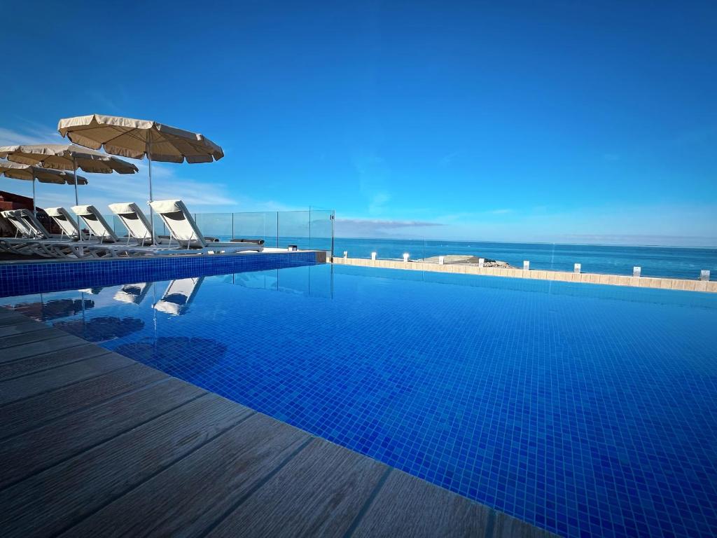 a swimming pool with chairs and umbrellas and the ocean at H10 Costa Adeje Palace in Adeje