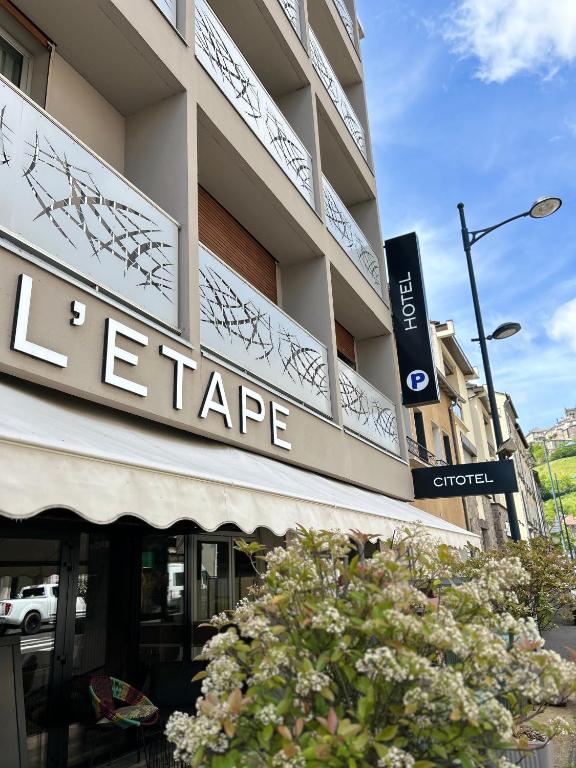 un grand bâtiment avec un panneau indiquant un magasin dans l'établissement Cit'Hotel L'Etape, à Saint-Flour