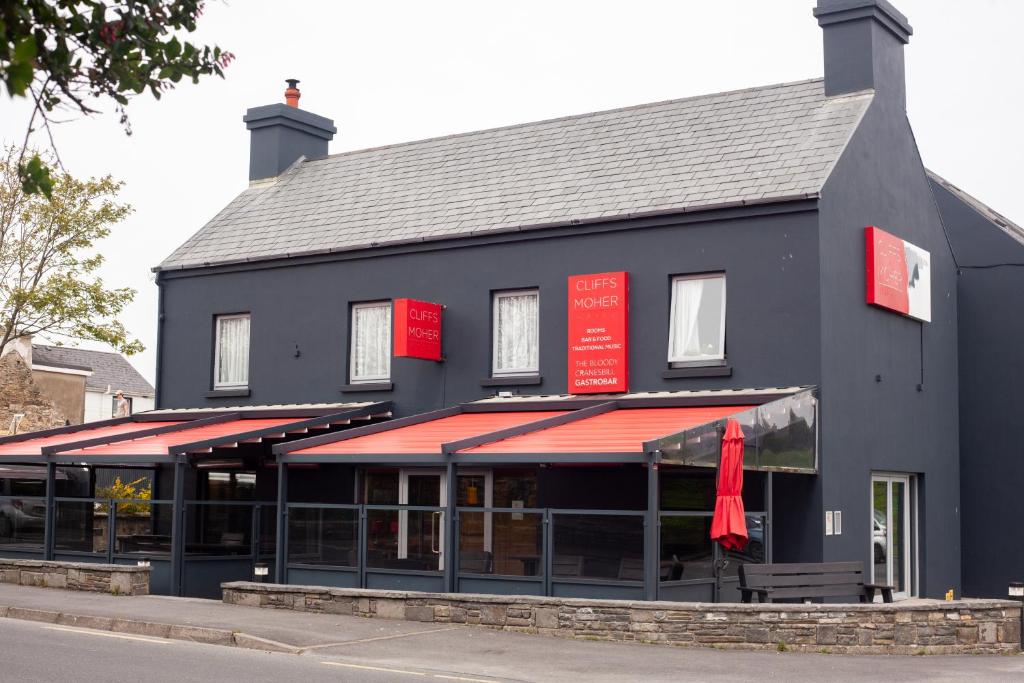 a black building with red signs on the front of it at Cliffs of Moher Hotel in Liscannor