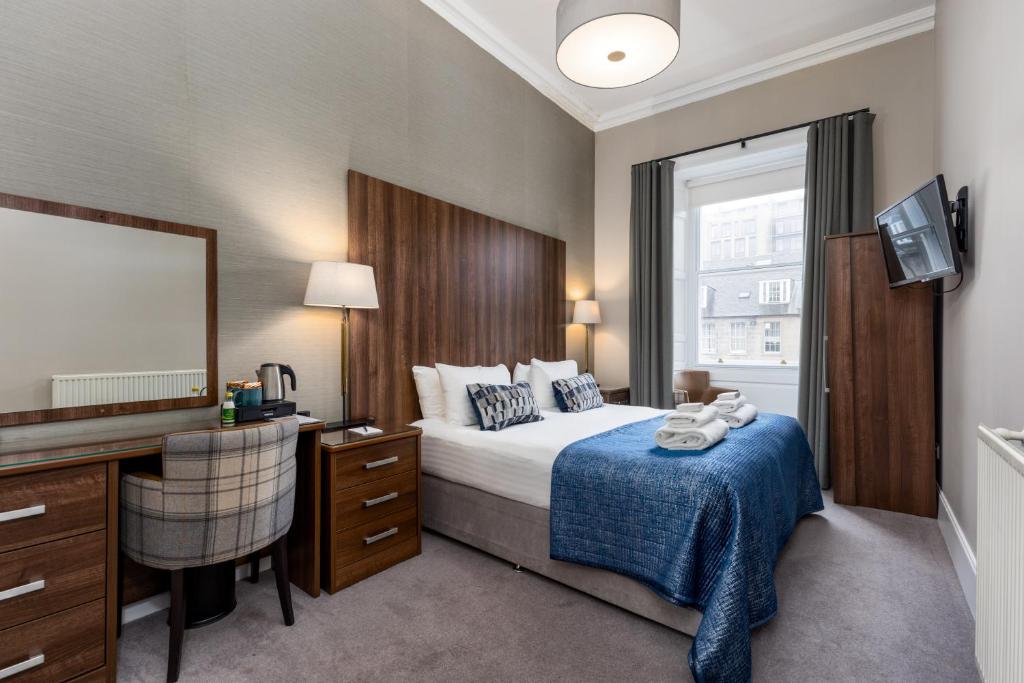 a bedroom with a bed and a desk and a mirror at 28 York Place Hotel in Edinburgh