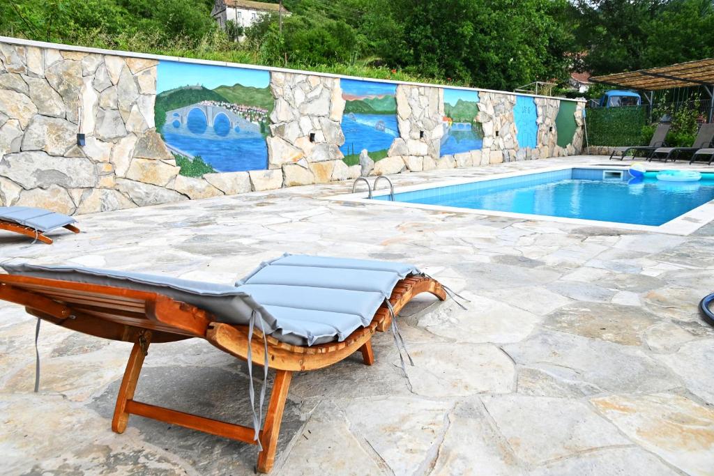 una piscina con un sillón frente a una pared en Gazdinstvo Vukanović - Kuća za odmor, en Trebinje