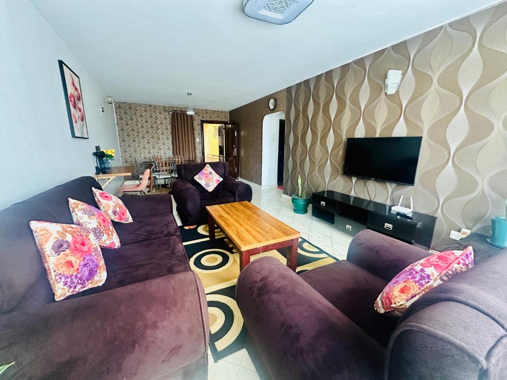 a living room with purple couches and a wooden table at Milimani apartments10 in Nakuru