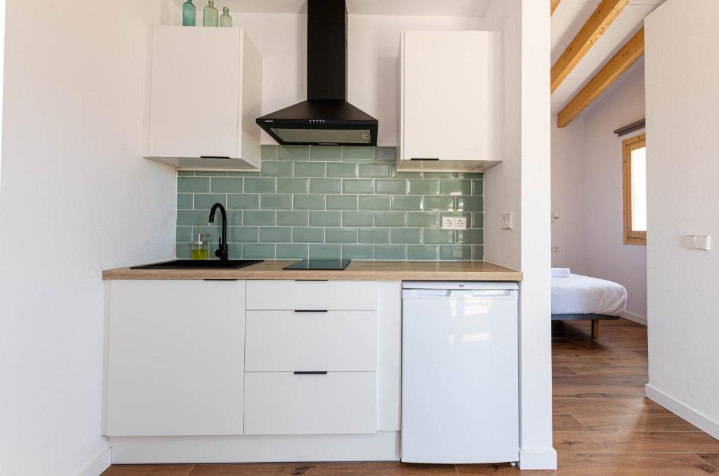 uma cozinha com armários brancos e uma parede de tijolos verdes em Agroturismo Cal Tio 3 YourHouse em Costitx