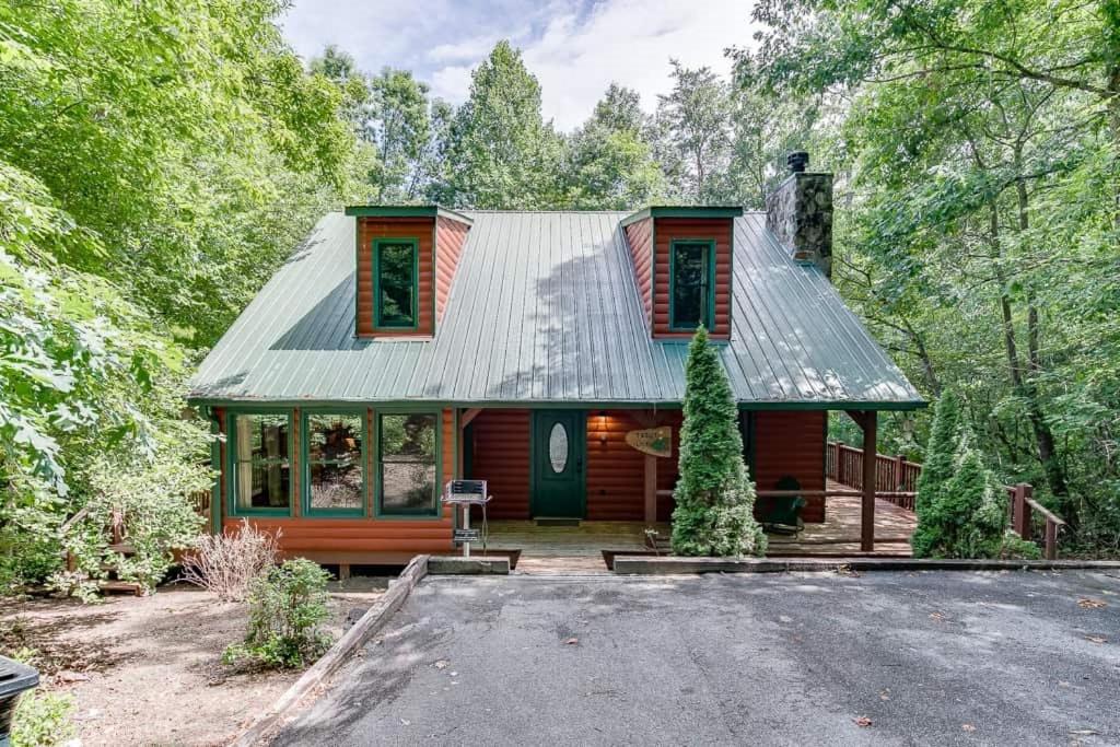 ein rotes Haus mit einem Metalldach im Wald in der Unterkunft Cabin with Jacuzzi & Hydrotherapy SpaNear Helen in Cleveland