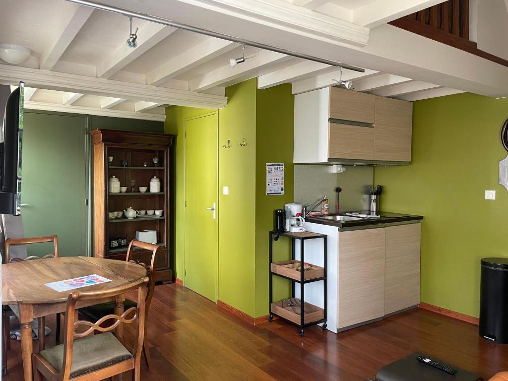 uma cozinha com paredes verdes e uma mesa de madeira em Duplex 1er étage résidence "L'anglais" centre Bayeux grande terrasse et jardin aménagé commun proche du plages du débarquement- parking gratuit à proximité em Bayeux