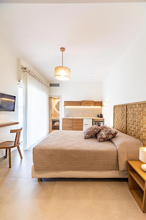 a bedroom with a large bed and a kitchen at Arancia Elegant Rooms and Suites in Tolo