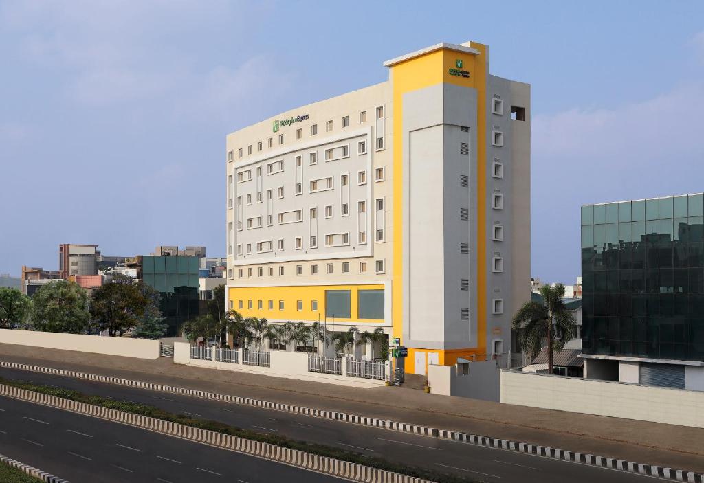 a white and yellow building next to a highway at Holiday Inn Express Chennai OMR Thoraipakkam, an IHG Hotel in Chennai