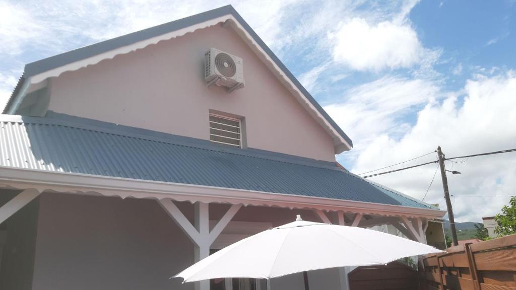 um edifício branco com um telhado verde e um guarda-chuva em Ka Villa Location em Pointe-Noire