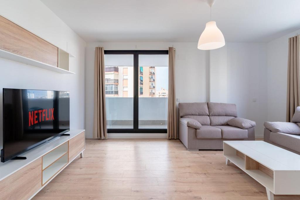 ein Wohnzimmer mit einem TV und einem Sofa in der Unterkunft GuestReady - Sunny Seaside Escape in Málaga in Málaga