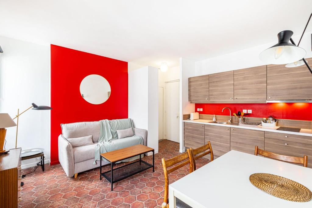 Il comprend un salon avec un mur rouge et une cuisine. dans l'établissement GuestReady - Charming stay near Belleville, à Paris