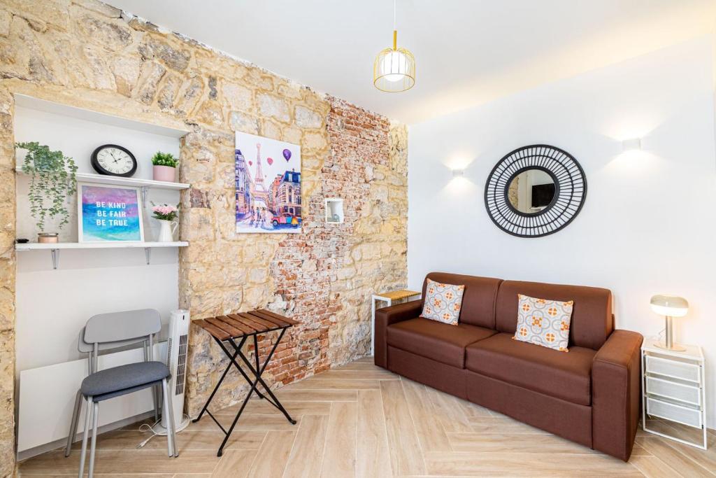 un salon avec un canapé et un mur de briques dans l'établissement GuestReady - Charming Getaway in Le Marais, à Paris