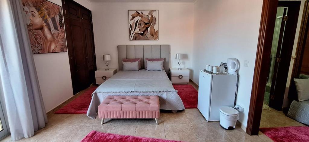 a bedroom with a bed and a pink chair at Casa Branca Pinhal in Nazaré