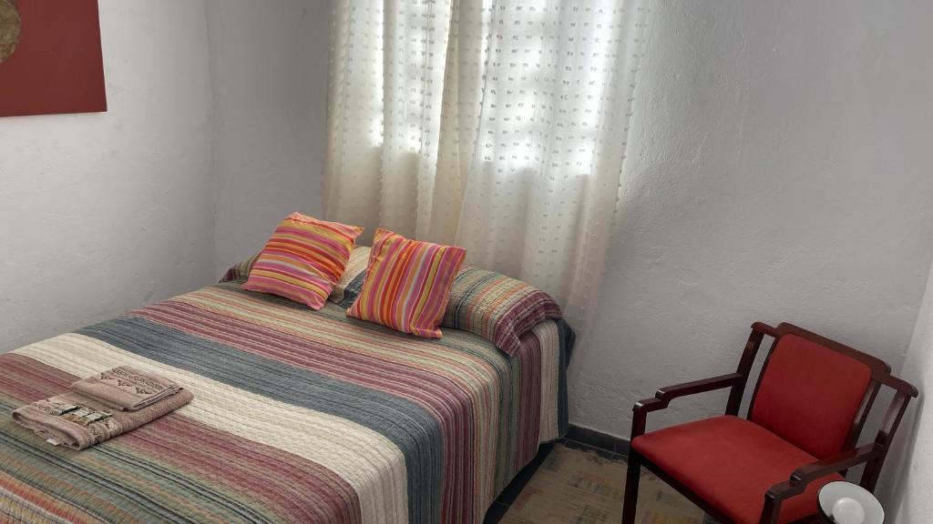 a small bedroom with a bed and a red chair at Loft Sousas in Campinas
