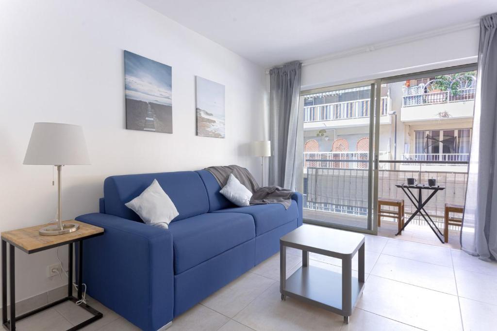 ein blaues Sofa im Wohnzimmer mit großem Fenster in der Unterkunft GuestReady - Cannes Delight near Mouré Rouge Port in Cannes