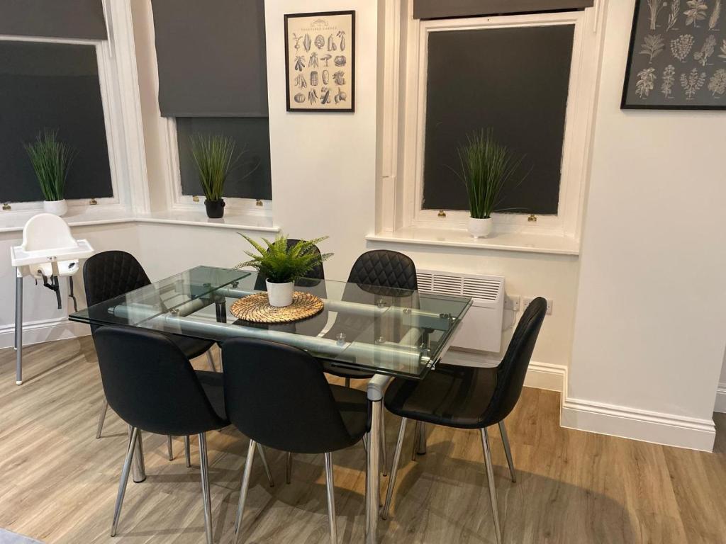 una sala da pranzo con tavolo in vetro e sedie nere di Flat 2 ,559 Wimborne Road a Bournemouth