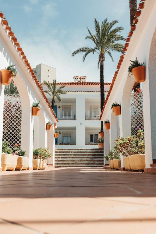 a boardwalk in front of a building with palm trees at Los Bungalows Del Arenal in Jávea