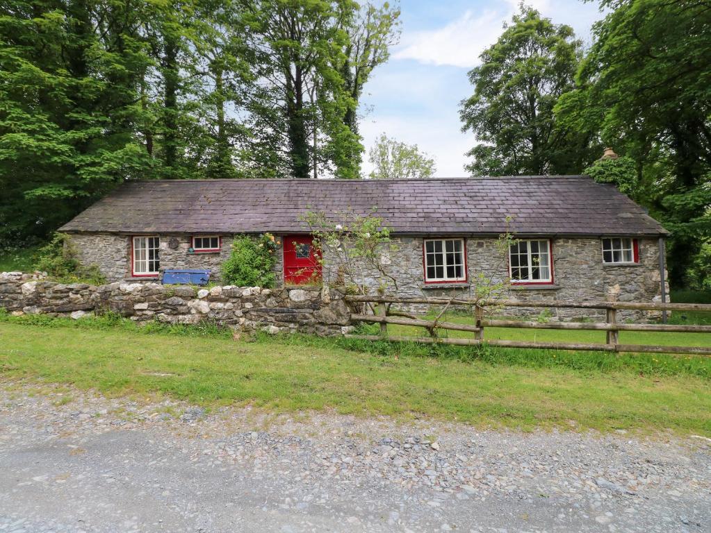 an old stone house with a wooden fence at Penyrallt Fach Cottage in Llandysul
