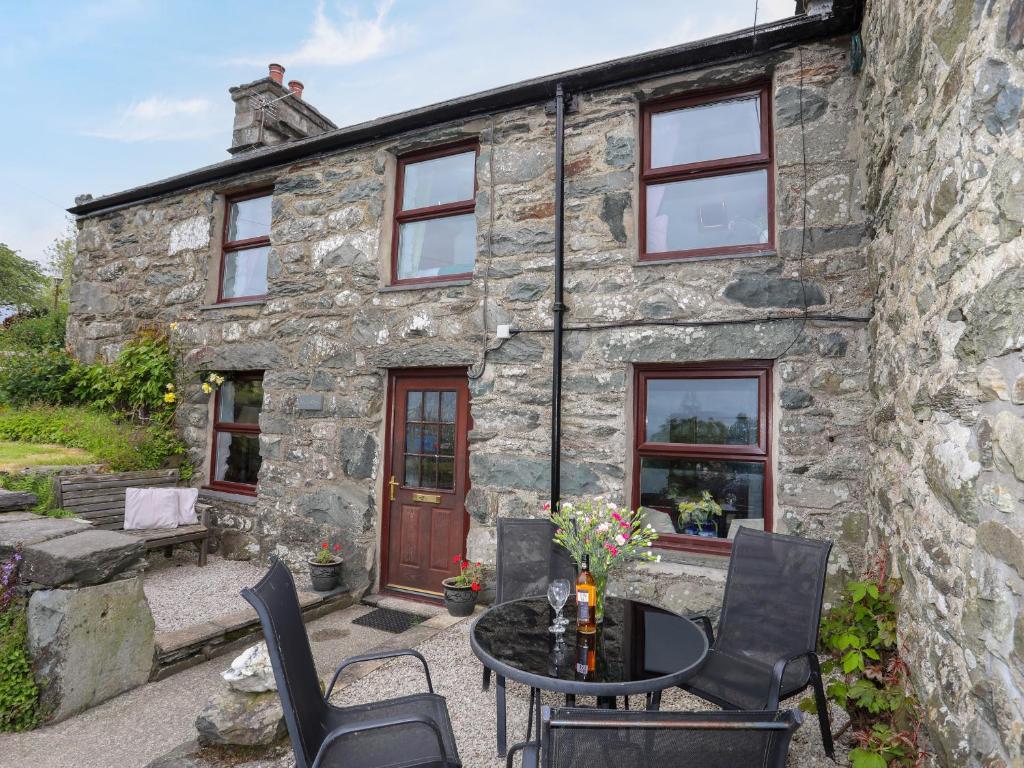 a stone house with a table and chairs in front of it at Hendy Cottage in Llanbedr