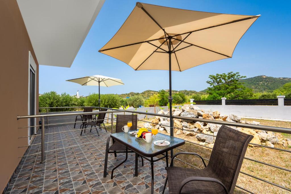 a patio with a table and an umbrella at Pervolia Studios Near Airport in Kremasti
