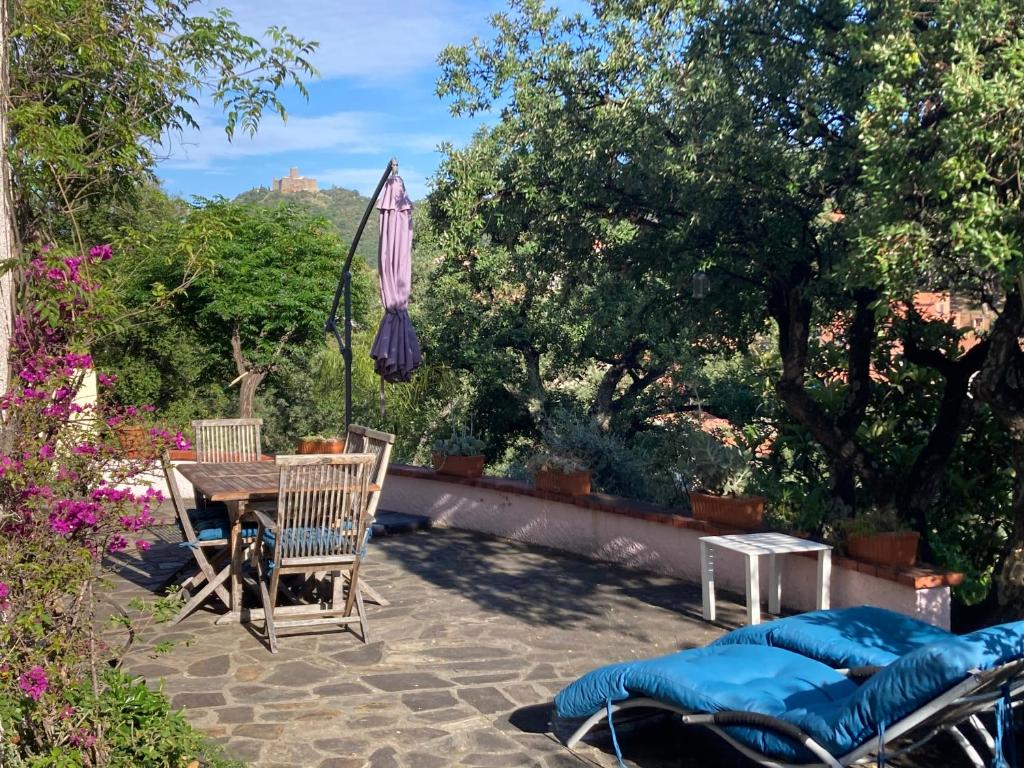 eine Terrasse mit einem Tisch, Stühlen und einem Sonnenschirm in der Unterkunft Appartement 3 pièces et jardin in Collioure