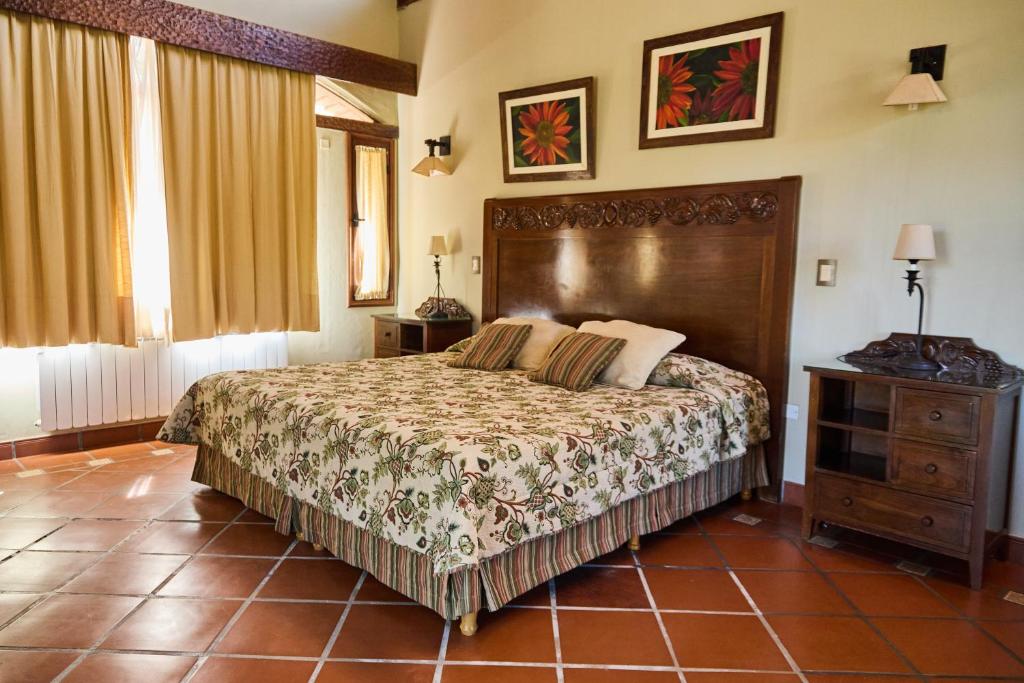 a bedroom with a large bed with a wooden headboard at La Casa De La Bodega - Wine Boutique Hotel in Cafayate
