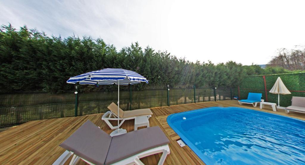 a patio with a pool and an umbrella and chairs at EDİ Group Turizm Sapanca Villas in Sapanca
