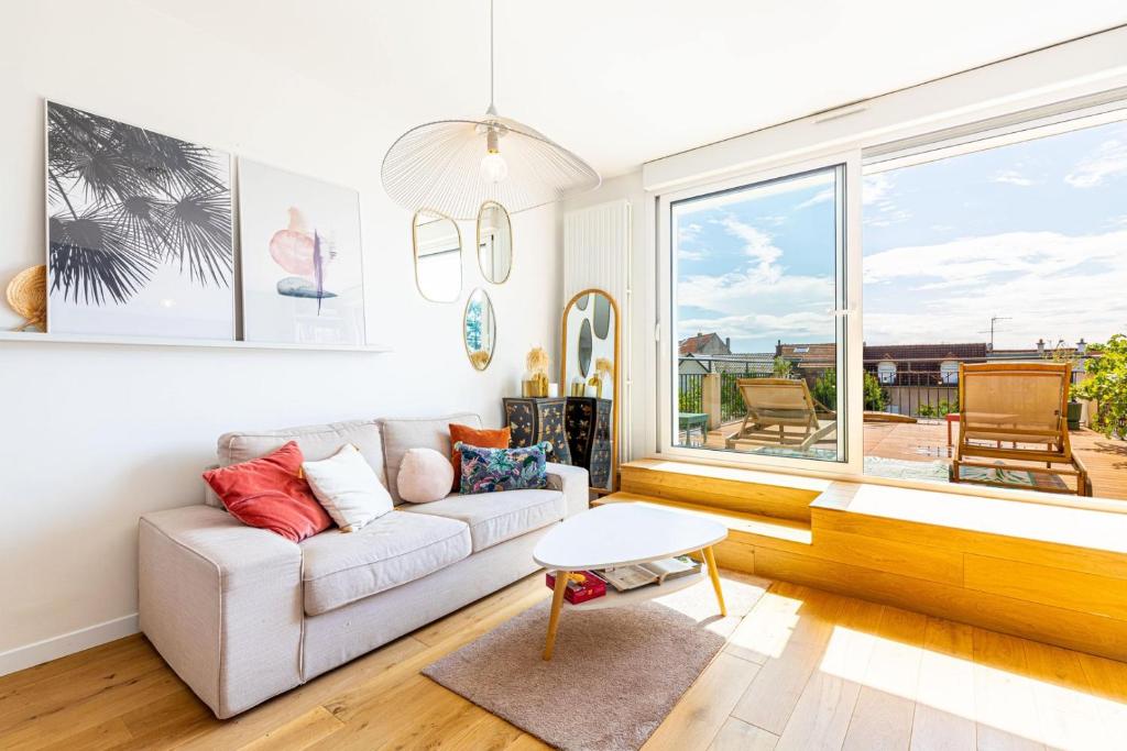 ein Wohnzimmer mit einem weißen Sofa und einem großen Fenster in der Unterkunft GuestReady - Exquisite and calm getaway in Nogent-sur-Marne
