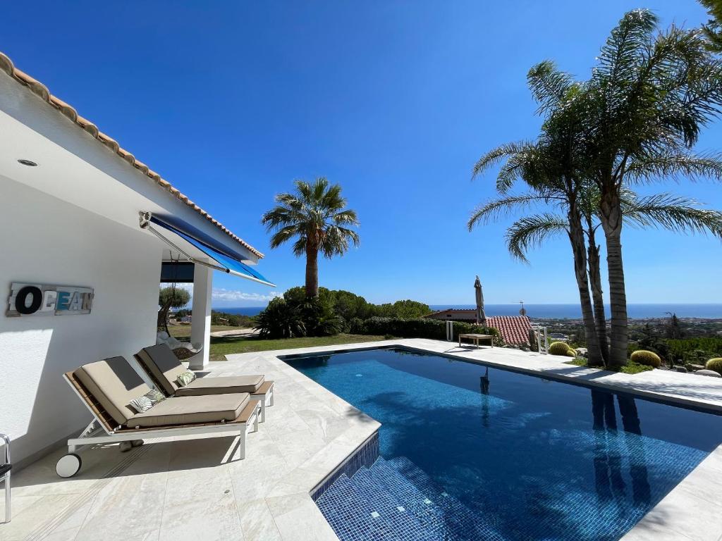 uma villa com piscina e palmeiras em Palm Maresme - Suite with bathroom and living-room and terrasse with ocean views in a private villa em Vilassar de Dalt
