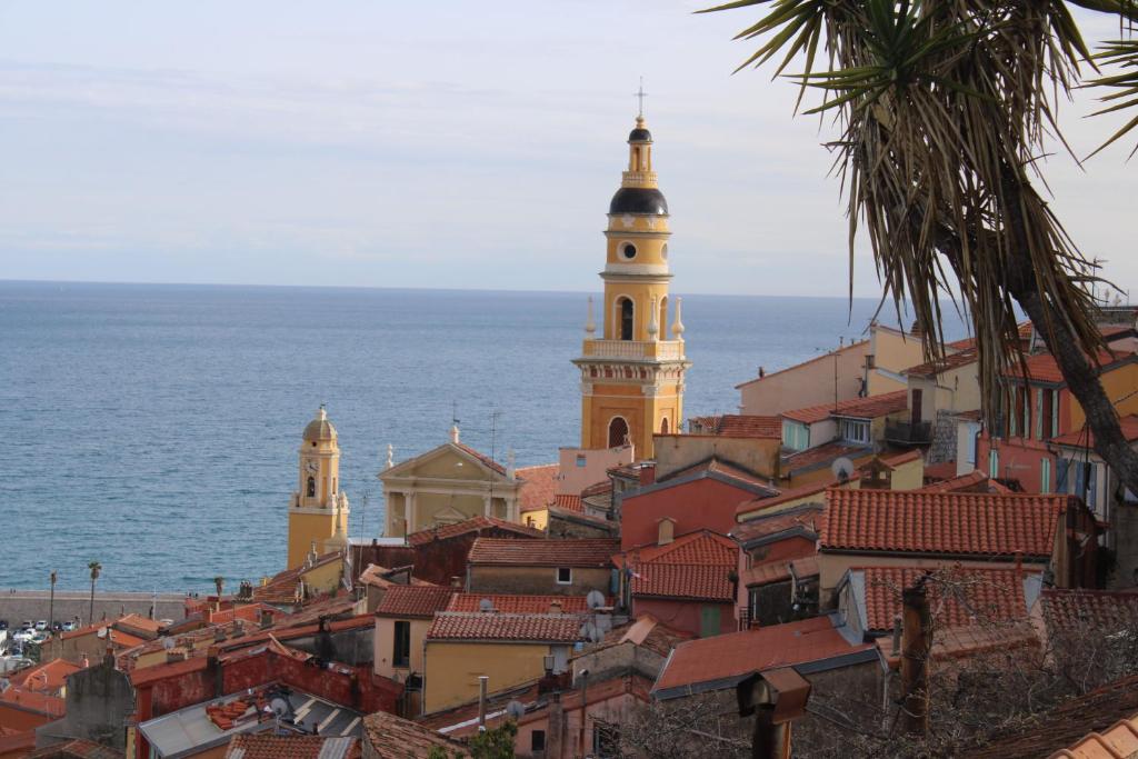 een uitzicht op een stad met een klokkentoren en de oceaan bij Victoria Palace in Menton
