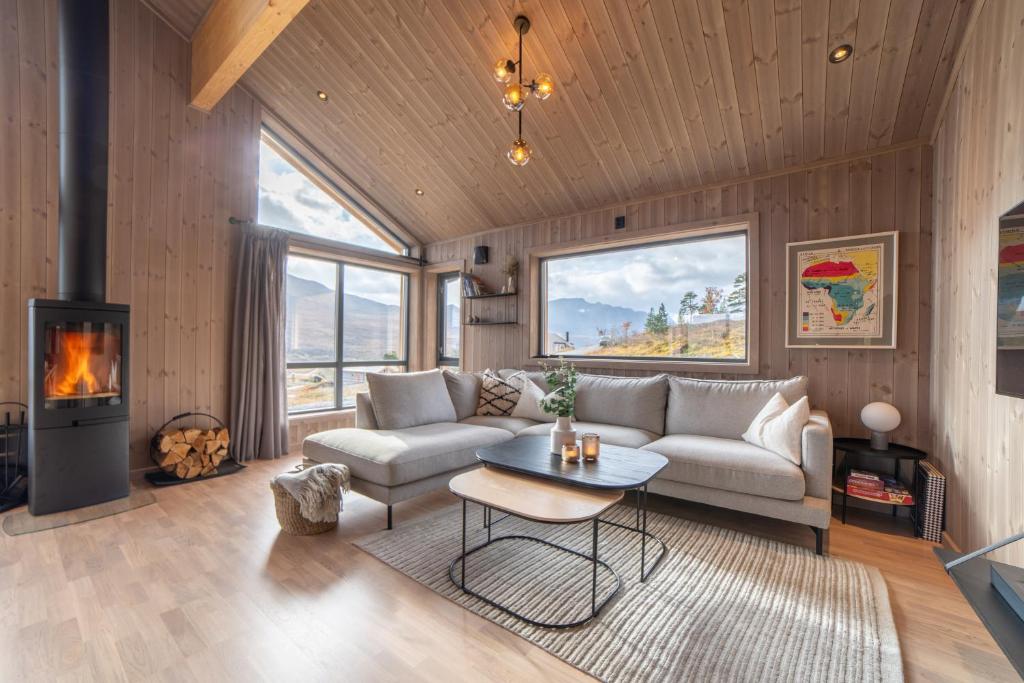 sala de estar con sofá, mesa y chimenea en Fjellsætra Sunnmøre Hideaway, Mountain View & Private Sauna en Sykkylven