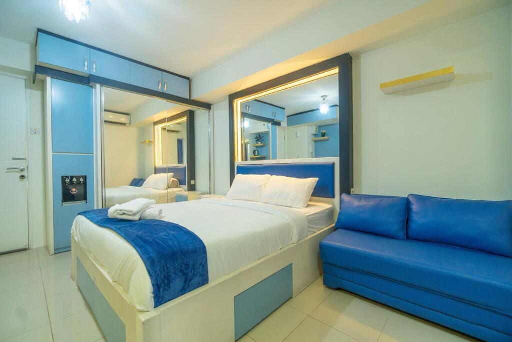 a bedroom with a bed and a blue couch at Studio at Bassura City East Jakarta Netflix in Jakarta