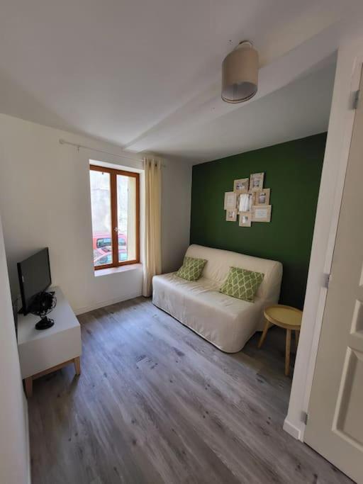 - un salon avec un canapé blanc et un mur vert dans l'établissement Paisible maison de village avec terrasse, à Fleury