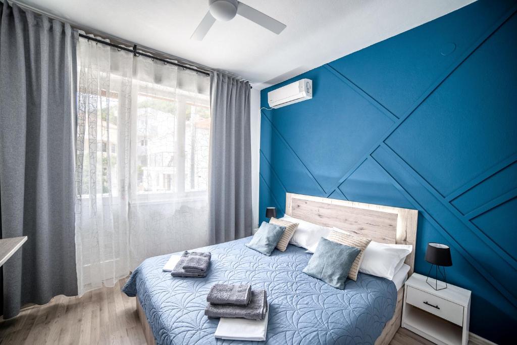 a blue bedroom with a bed with a blue wall at Wind Rose Rooms in Baška Voda