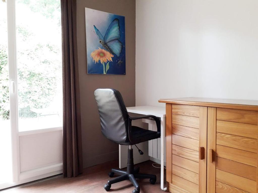 a office with a chair and a desk and a butterfly painting at Chambre Salon Sdb Jardin près Bordeaux in Cestas