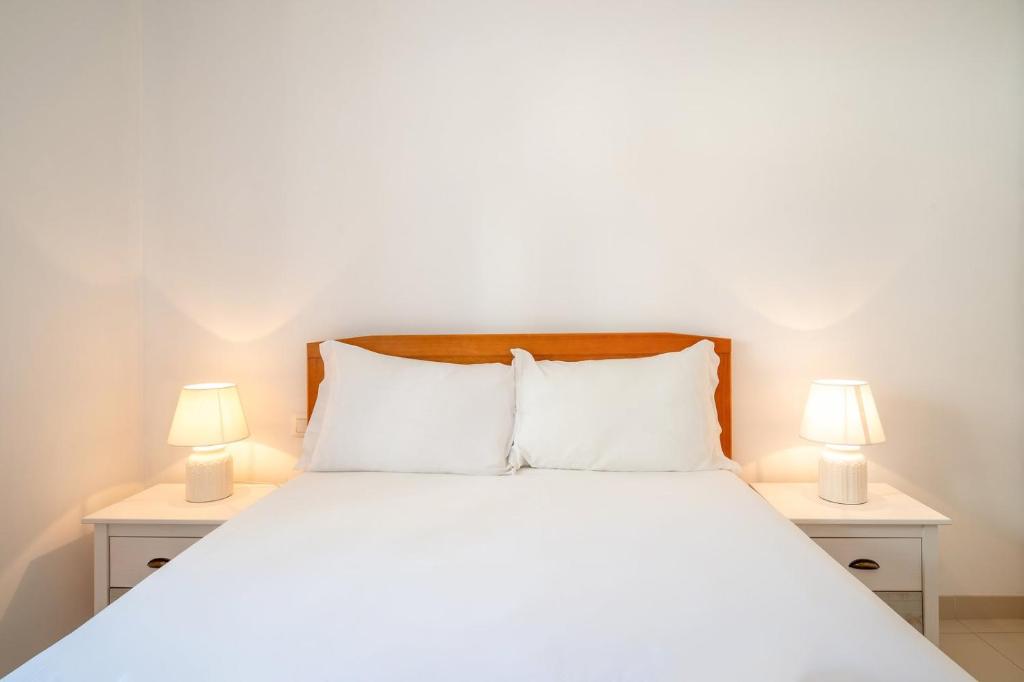 een slaapkamer met een wit bed en 2 lampen bij GuestReady - Relaxation near Carcavelos Beach in Carcavelos